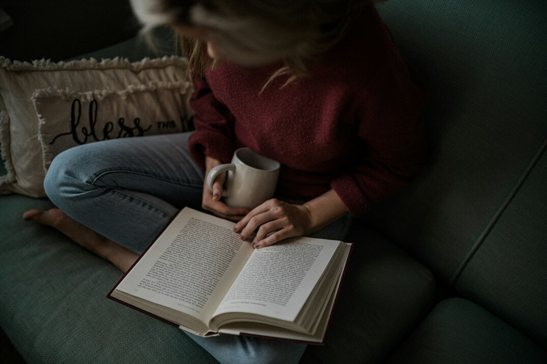 person reading book in cozy chair