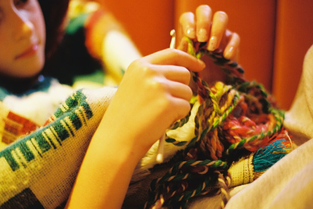 person knitting a scarf